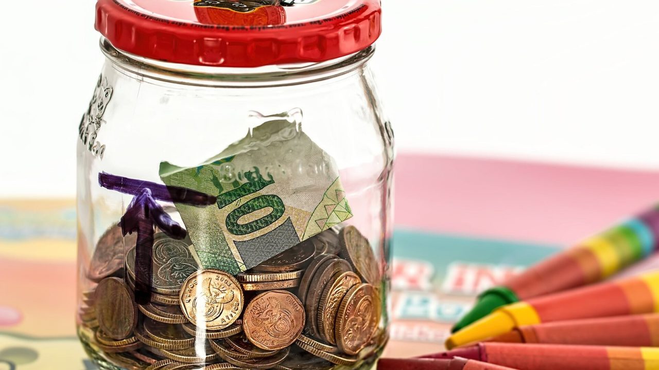A simple piggy bank made from a glass jar holding coins